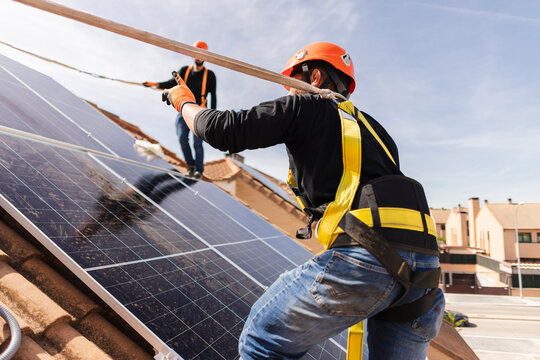 Workers installing solar panels on residential rooftop