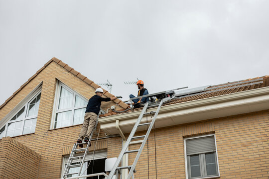 Workers installing solar panels on residential building roof