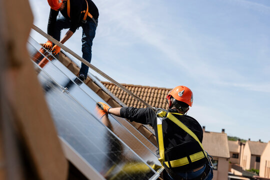 Workers installing solar panels on residential roof
