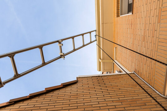 Extending ladder resting against building wall and roof