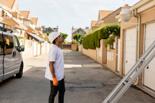 Handyman wearing hard hat inspecting residential property exterior