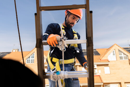 Worker wearing safety harness preparing to work on ladder