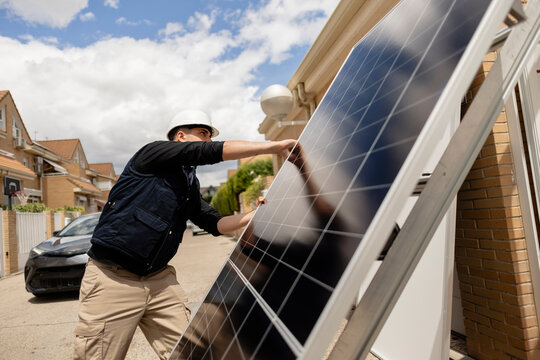 Technician installing solar panel on residential building roof