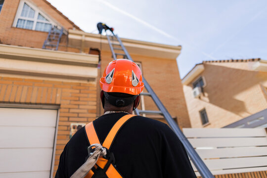Worker with safety gear watching colleague on roof