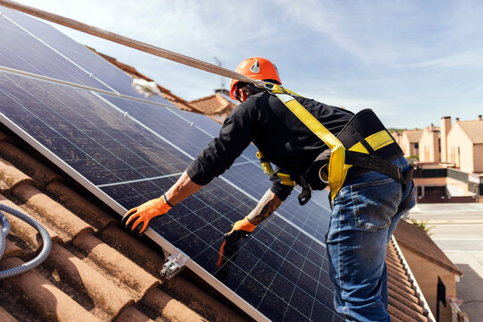 Technician installing solar panels on residential roof