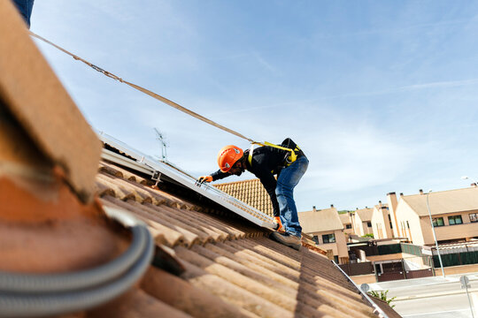 Worker installing solar panels on residential roof