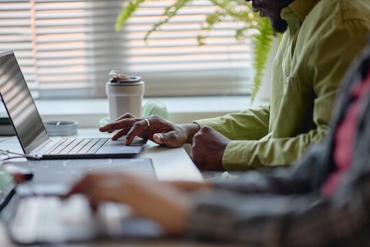 Close up of Black man using laptop during team collaboration at desk, supporting remote work and digital productivity. Ideal for business communication, coworking, training