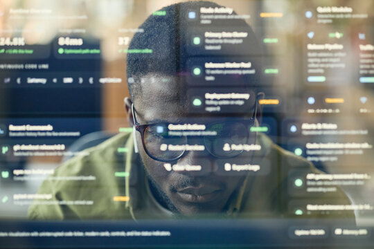 Close up of young Black man analyzing software dashboard on computer, monitoring data and coding workflow. Ideal for cybersecurity, analytics, fintech, remote tech work