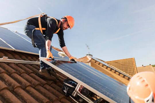 Engineer installing solar panel on residential rooftop