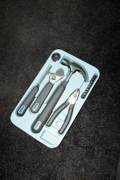 Hand holding a toolkit full of building tools such as hammer, pliers, 