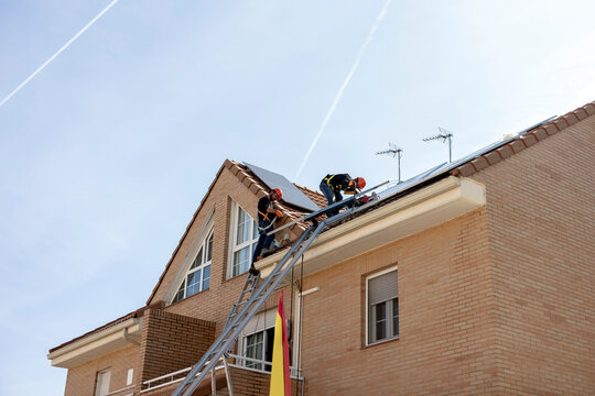 Workers installing solar panels on residential house roof