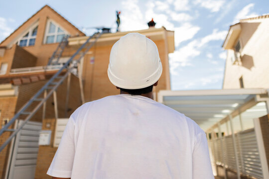Employee in hard hat supervising residential construction workers