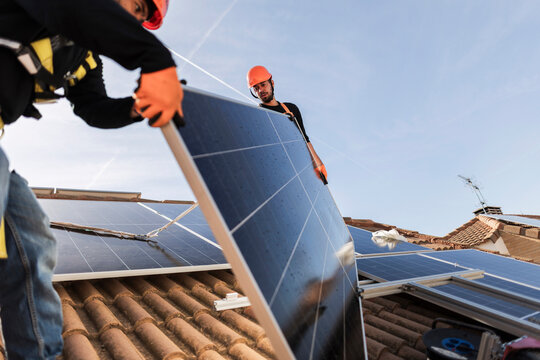 Workers installing solar panel for clean energy on roof