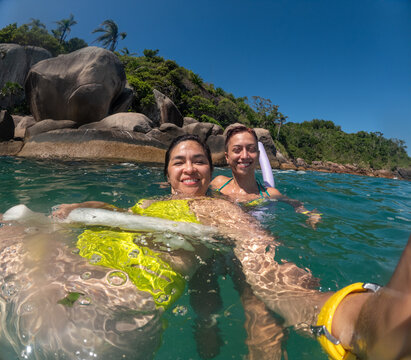 UGC Two Friends Swimming in Clear Water on a Sunny Day Near Rocks