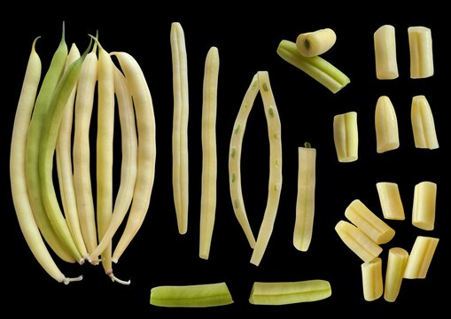 Collection of fresh yellow string beans on black background, whole pod cluster, halved lengthwise and chopped pieces.