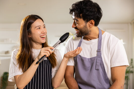 Couple kitchen interview microphone apron woman man smile cooking home, cheerful adults in apron sharing playful talk with microphone during casual food content recording indoors