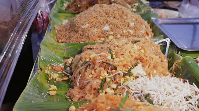 Street Food Vendor Selling Variety of Stir Fry Rice Pad Thai Noodles, Pad Mee Korat (Northeast Thailand Style Stir Fried Noodles). Bangkok Open Night Market
