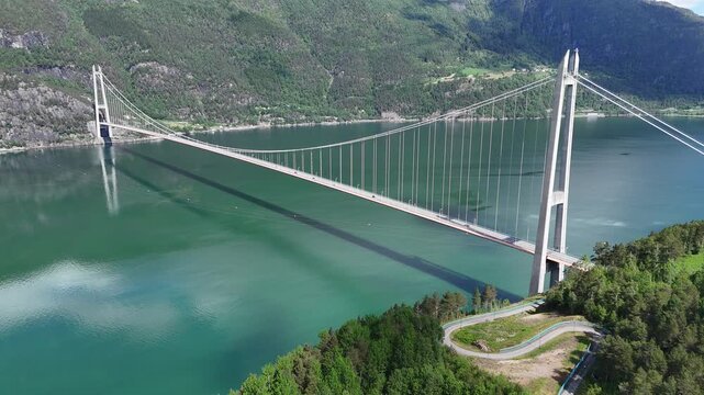 Aerial drone pan of Hardangerbrua suspension bridge between mountain cliffs over a river, Norway
