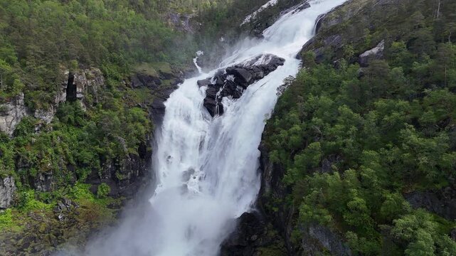 Aerial drone right to left of Nyastolfossen valley surrounded by forest, Norway