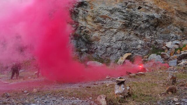 A multinational group of male soldiers in infantry uniforms, carrying paintball guns and ready for combat, were seen running and practicing military drills, with pink smoke signals being sent 