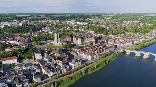 Drone footage showcasing the picturesque cityscape of Gien, located in central France. The clip features a sweeping aerial view of the historic town with its iconic church, traditional rooftops, and