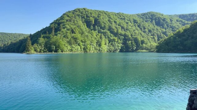 Turquoise lake surrounded by forested hills in Plitvice Lakes National Park, Croatia. 