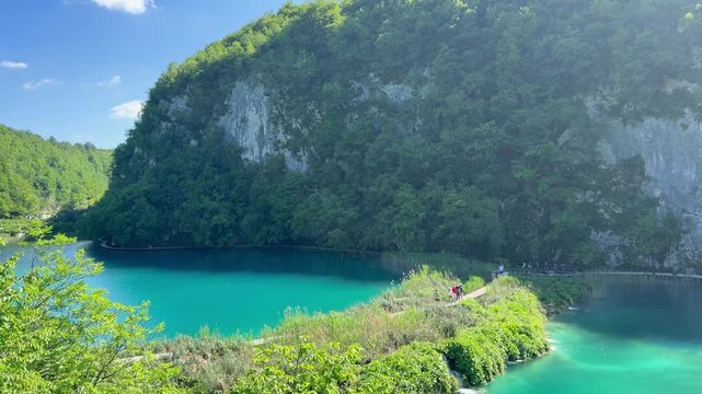 Plitvice Lakes National Park, Croatia - May 2026: Visitors walking along wooden pathways near turquoise lake and limestone cliffs in Plitvice Lakes National Park.