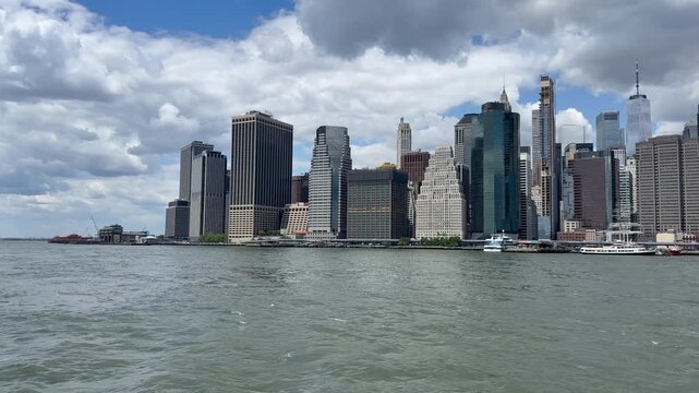 Panoramic, scenic view of Lower Manhattan. Financial district. Motion of East River waves. Cars traffic on FDR drive, road. New York City, United States