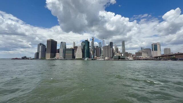 Panoramic, scenic view of Lower Manhattan. Financial district. Motion of East River waves. Cars traffic on FDR drive, road. New York City, United States