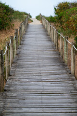 Obraz premium Rustic wooden footway with rope railing guiding towards sea shore