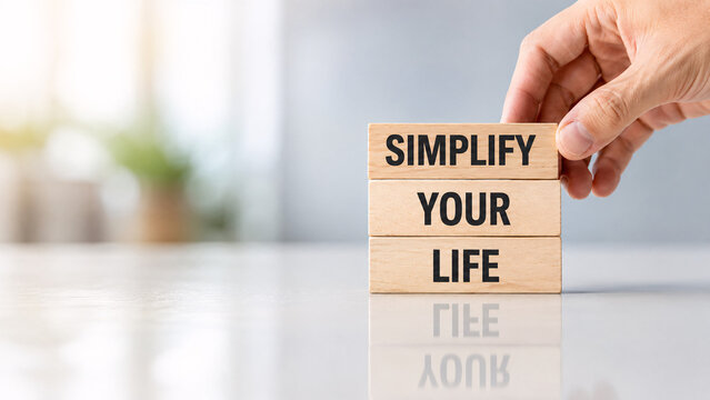 Hand arranging wooden blocks with text simplify your life on bright background. Concept of minimalism, lifestyle choice, stress reduction, and personal development.