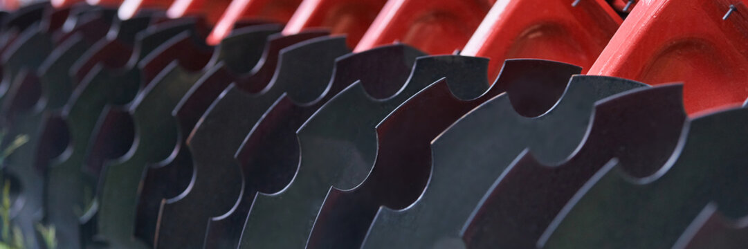 Agricultural Disc Harrow Blades Aligned On Red Frame In Close Up Detail Showing Curved Steel Discs Mounted On Farm Machinery For Soil Tillage And Implement Maintenance.
