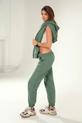 Full-length portrait of a confident young woman wearing a trendy tracksuit and chunky sneakers, standing  in a minimalist studio against a white background. © neonshot