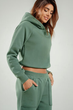 Portrait of a confident young woman wearing a trendy tracksuit  standing in a minimalist studio. Modern casual streetwear, athleisure fashion, comfortable outfit, urban style