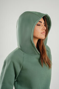 Portrait of a confident young woman wearing a hoodie posing in studio. Modern casual streetwear, athleisure fashion, comfortable outfit, urban style