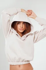 Portrait of a confident young woman wearing a trendy tracksuit  with hoodie standing in a minimalist studio. Modern casual streetwear, athleisure fashion, comfortable outfit © neonshot