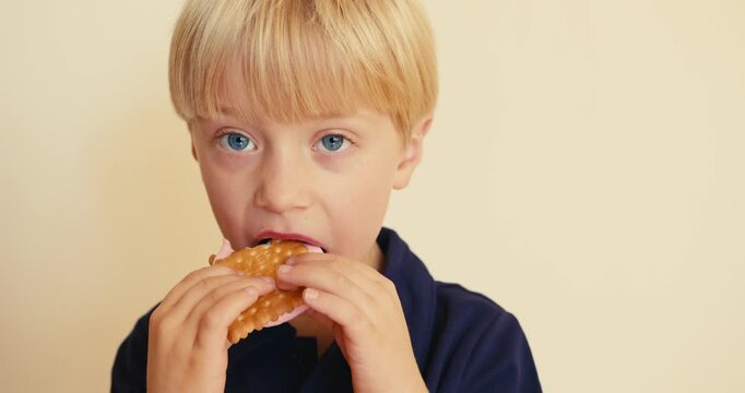 Cute blond boy eating pink ice cream sandwich