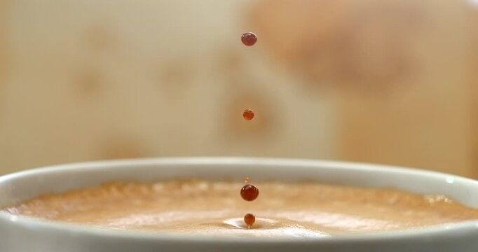 Espresso coffee drop creating a splash and ripple in crema, super slow motion