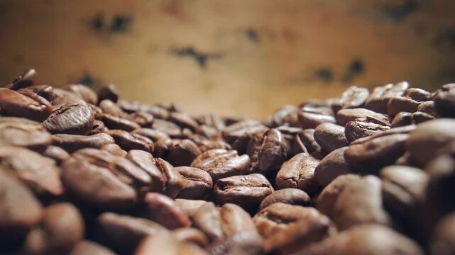 Roasting coffee beans process with smoke rising in slow motion from freshly roasted seeds on dark background