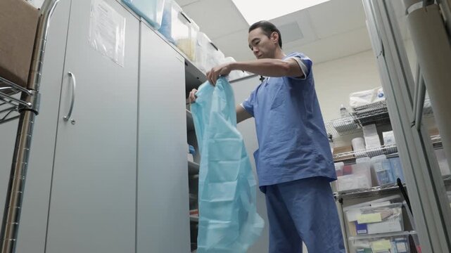 Male nurse doctor puts on personal protective equipment PPE N95 mask, face shield, glove, gown suit in hospital clinic. Medical personnel hygiene safety protection during outbreak pandemic