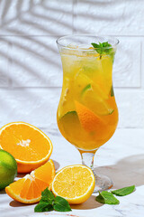 Fototapeta premium Refreshing drink with citrus fruits and mint leaves, on a marble surface, with shadows from palm leaves,sunlight, no people