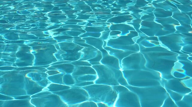 Shining azure swimming pool water with sunbeams creating rippled light patterns and abstract background texture