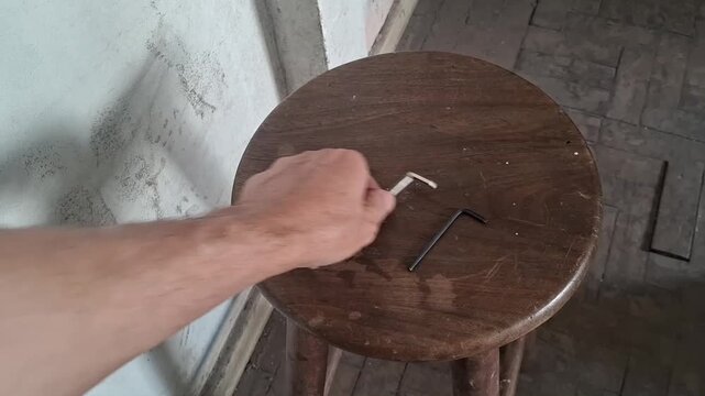 Hand picking up metal hex keys from wooden stool video motion