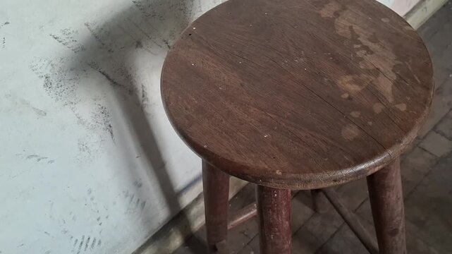 Weathered wooden stool standing in a dimly lit room video footage