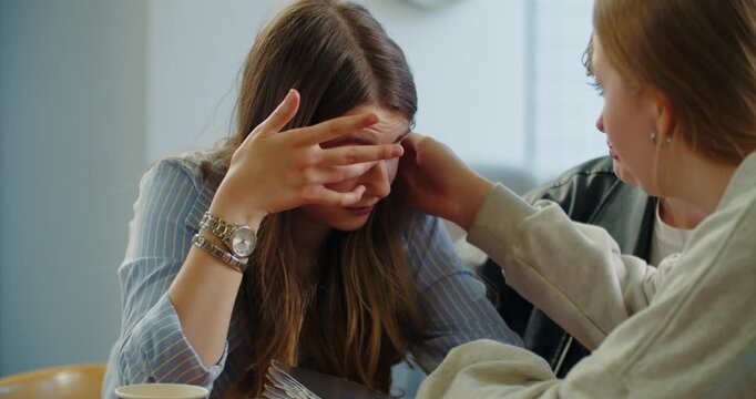 Teenage girl covering face while friends offer emotional support