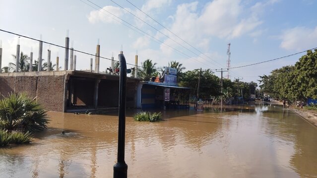 Flooded street with submerged buildings in a rural landscape under daylight