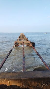 Rusty pier extends into calm sea on sunny day