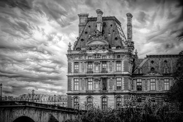 Obraz premium Black and white image of Ecole du Louvre in Paris, France. Captures the historical architecture under dramatic skies.