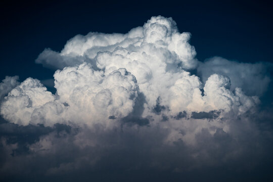 View of large white cumulus clouds against a deep blue sky over the Arashan lake area in Pop District, Namangan Region, Uzbekistan.