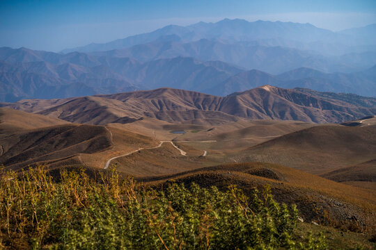 View of Arashan Lake surrounded by arid rolling hills and winding mountain roads in Pop District, Namangan Region, Uzbekistan.